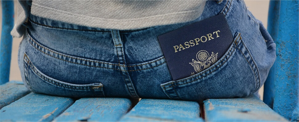 Person sittong on a bench with their passport hanging out of their pocket