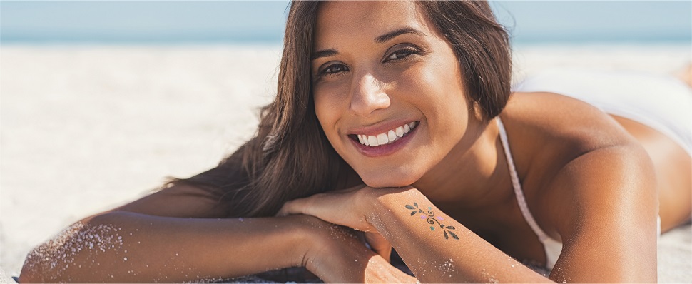 Lady with tattoo on arm lying on a beach